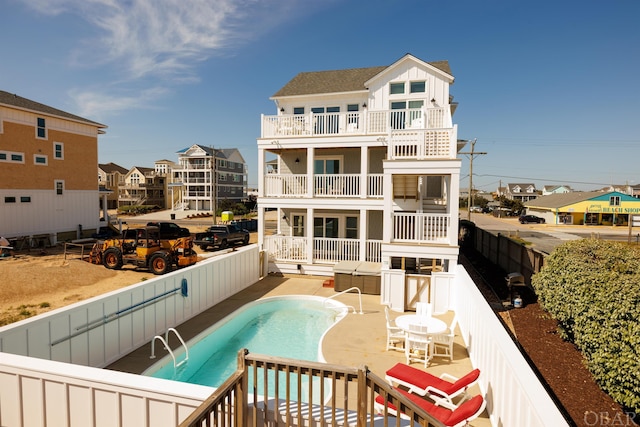 rear view of property featuring a fenced backyard, a balcony, a residential view, a fenced in pool, and board and batten siding