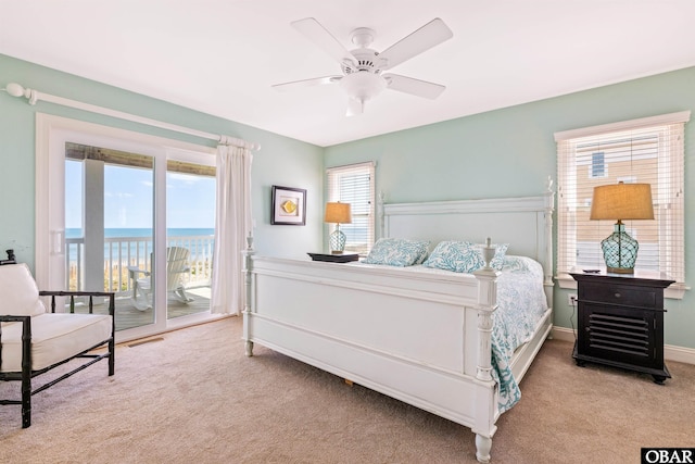 bedroom with ceiling fan, light carpet, a water view, baseboards, and access to exterior