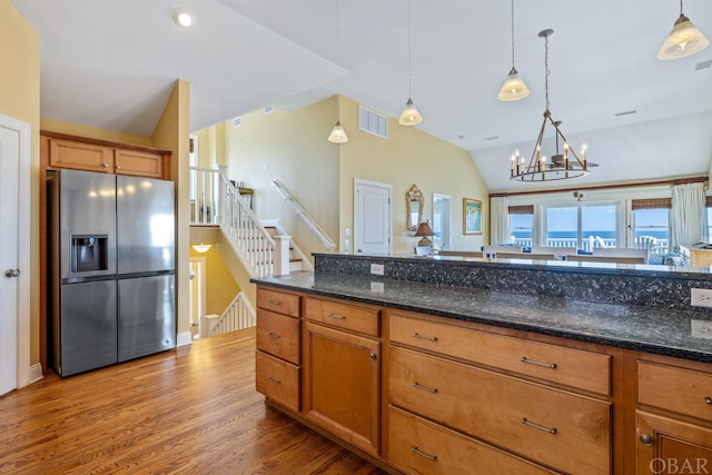 kitchen featuring lofted ceiling, brown cabinets, decorative light fixtures, and stainless steel fridge with ice dispenser