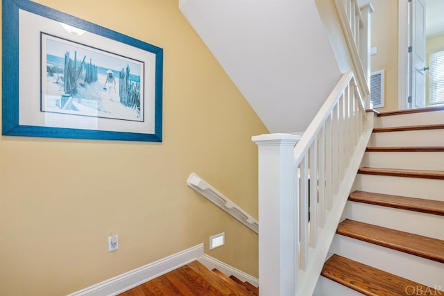 staircase featuring visible vents, baseboards, and wood finished floors