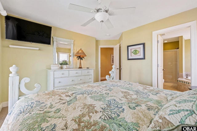 bedroom with ensuite bath, baseboards, and a ceiling fan