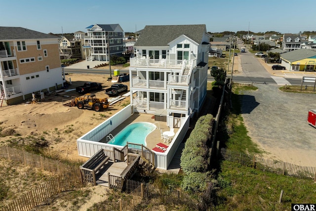 rear view of house with a residential view, a fenced backyard, a balcony, and a fenced in pool