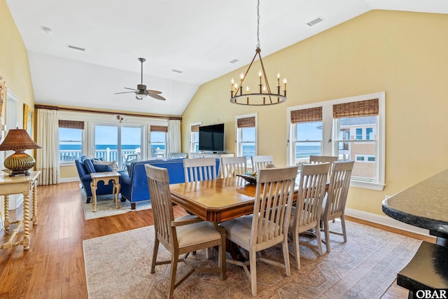 dining space with visible vents, vaulted ceiling, baseboards, and wood finished floors