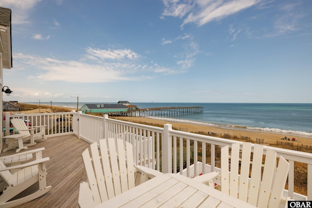 wooden deck featuring a water view and a beach view