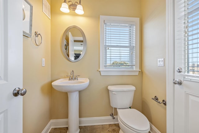 bathroom featuring toilet, a healthy amount of sunlight, visible vents, and baseboards