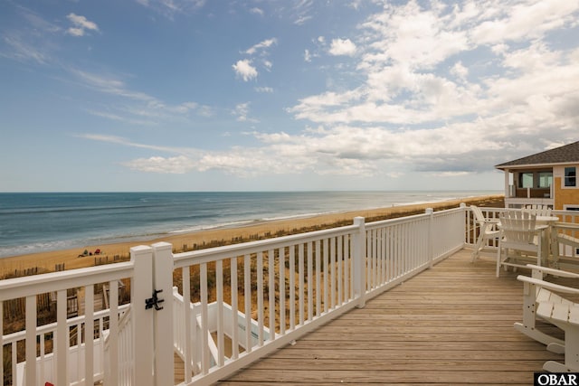 wooden deck featuring a water view and a view of the beach