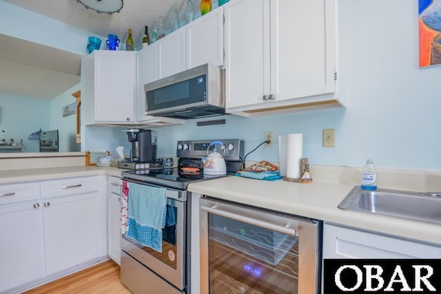 kitchen featuring white cabinetry, wine cooler, appliances with stainless steel finishes, and light countertops