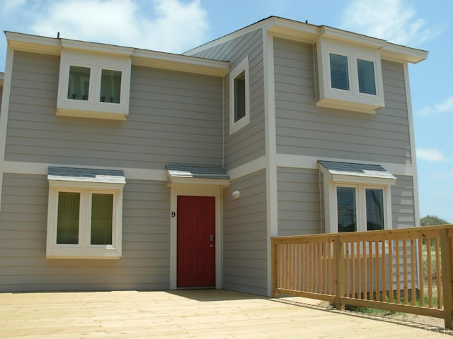 view of front facade featuring a shingled roof and a deck