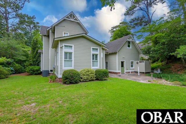 102 William And Mary Way Lot 13, Manteo, NC 27954 - back of house featuring central AC unit, a lawn, a patio area, and a shingled roof