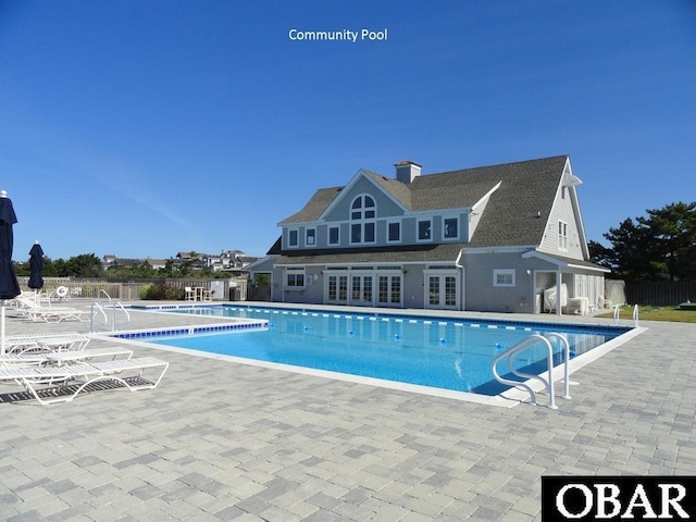 community pool with french doors, fence, and a patio