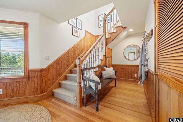 stairs featuring wainscoting, wood walls, and wood finished floors