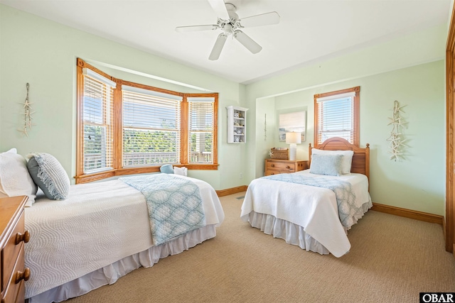 bedroom with a ceiling fan, light carpet, and baseboards