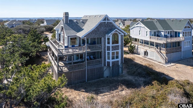 back of property with driveway, a chimney, and a balcony