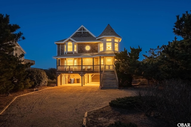 back of house at twilight with a carport, a porch, and stairway