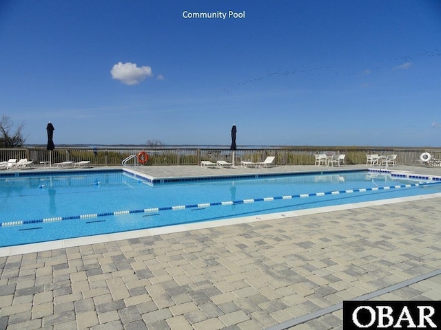 community pool with a patio area and fence