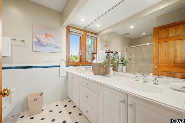 bathroom with recessed lighting, a sink, tile walls, double vanity, and a stall shower