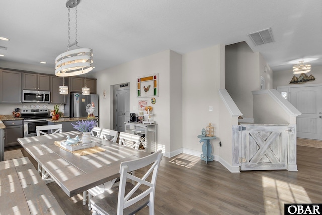dining room featuring a chandelier, wood finished floors, visible vents, and baseboards