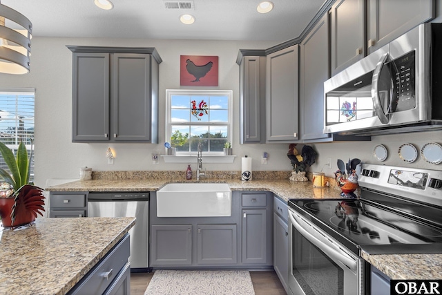 kitchen with a healthy amount of sunlight, gray cabinets, stainless steel appliances, and a sink