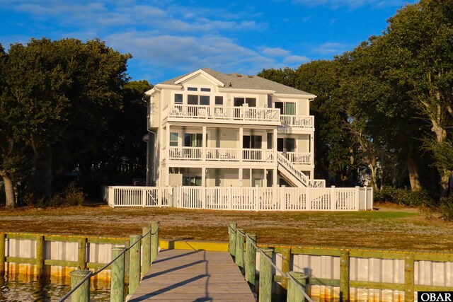 back of property with a water view, fence private yard, and a balcony