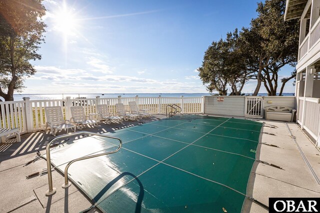 view of swimming pool featuring a water view and a gate