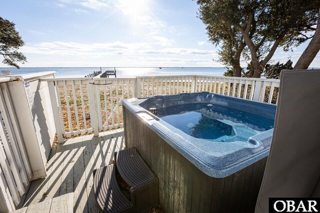 wooden deck with a beach view, a water view, and a hot tub