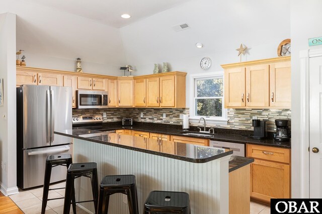 kitchen with stainless steel appliances, visible vents, light tile patterned flooring, a sink, and dark stone countertops