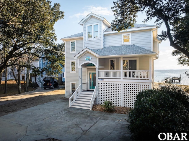 view of front of property with a porch, a water view, and roof with shingles