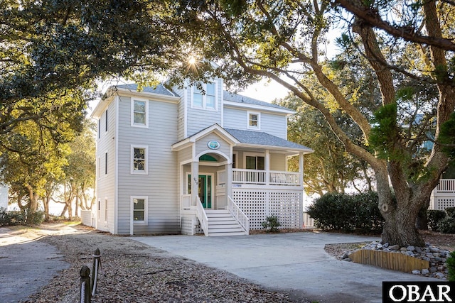 view of front facade featuring covered porch, concrete driveway, and roof with shingles