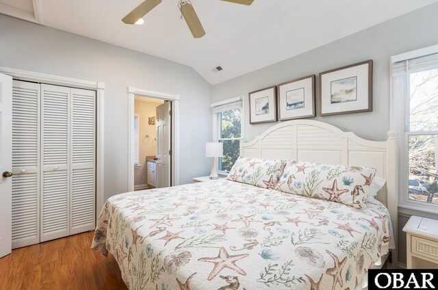 bedroom with a closet, ensuite bathroom, ceiling fan, vaulted ceiling, and wood finished floors