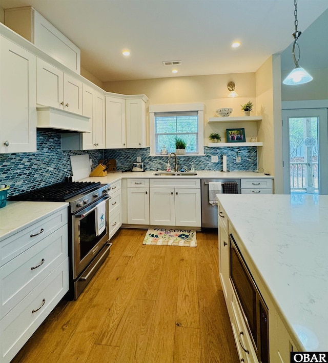 kitchen featuring pendant lighting, stainless steel appliances, custom exhaust hood, and white cabinets