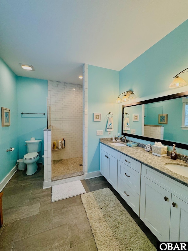 bathroom with a walk in shower, double vanity, a sink, and baseboards