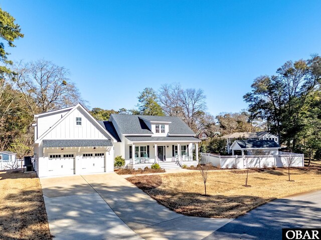 view of front of house featuring covered porch, a garage, a shingled roof, concrete driveway, and board and batten siding