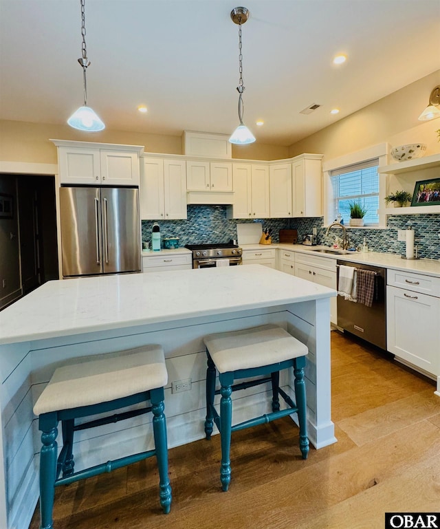 kitchen featuring white cabinetry, decorative light fixtures, a breakfast bar area, and high quality appliances