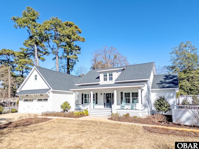 view of front of house with driveway, covered porch, a shingled roof, and a front lawn