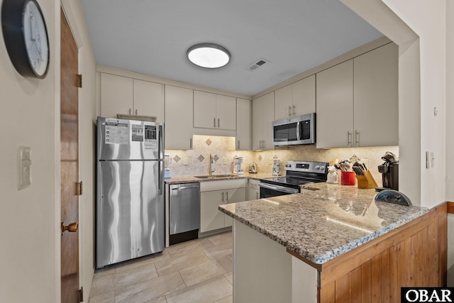 2035 S Virginia Dare Trl Unit 7, Kill Devil Hills, NC 27948 - kitchen with stainless steel appliances, a peninsula, a sink, light stone countertops, and tasteful backsplash
