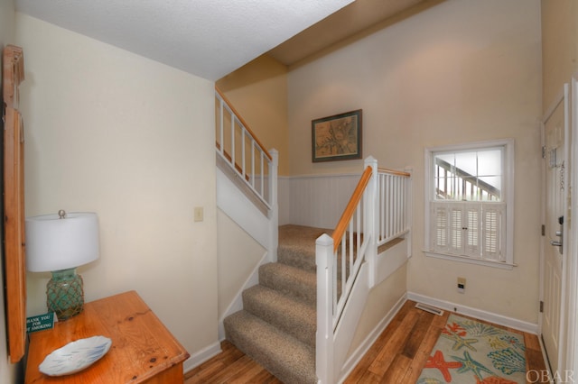 stairway with visible vents, baseboards, and wood finished floors