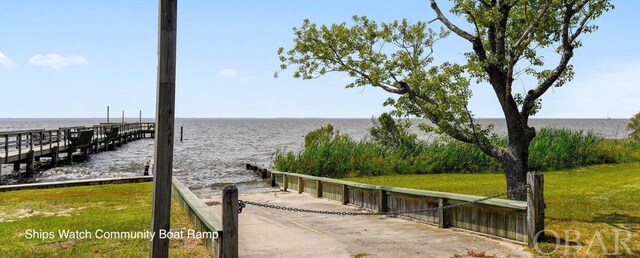 view of dock featuring a lawn and a water view