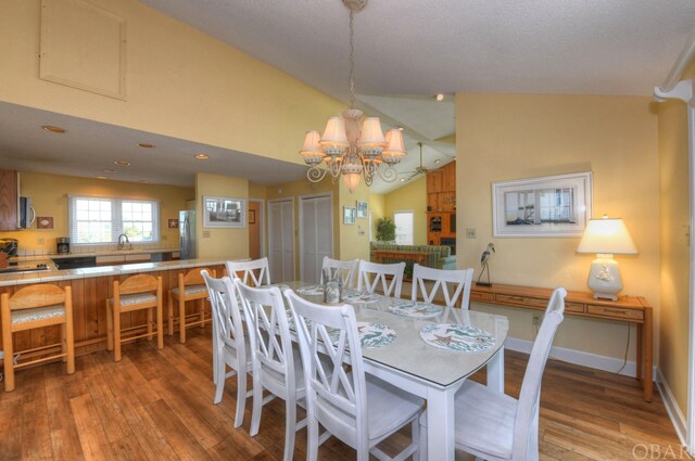 dining area featuring lofted ceiling, light wood finished floors, baseboards, and an inviting chandelier