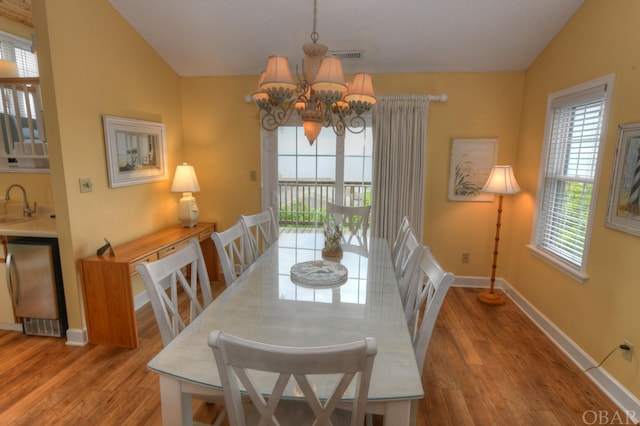 dining area with lofted ceiling, visible vents, light wood finished floors, and an inviting chandelier