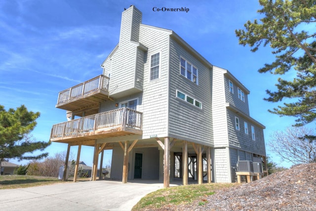 exterior space featuring a carport, concrete driveway, and a chimney