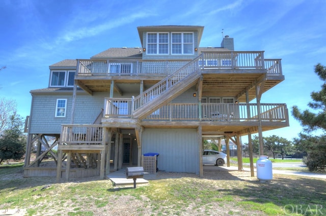 rear view of property with a shingled roof, a carport, and a wooden deck