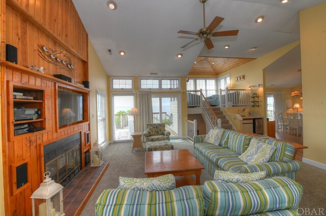 living area with stairway, dark colored carpet, a fireplace, high vaulted ceiling, and recessed lighting