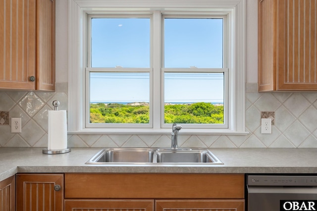 kitchen featuring stainless steel dishwasher, a sink, healthy amount of natural light, and light countertops