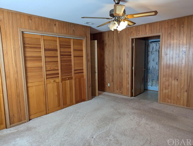 369 Lighthouse Rd Lot # 2, Ocracoke, NC 27960 - unfurnished bedroom featuring a closet, visible vents, light colored carpet, a ceiling fan, and wooden walls