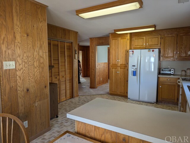 369 Lighthouse Rd Lot # 2, Ocracoke, NC 27960 - kitchen with white fridge with ice dispenser, brown cabinetry, light countertops, and wooden walls