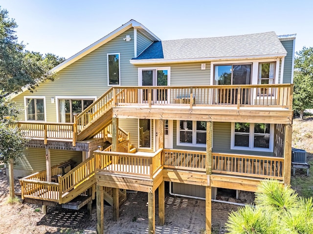 back of house featuring roof with shingles and a wooden deck