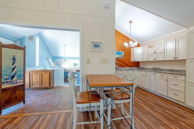 kitchen with dark wood-type flooring, white cabinetry, vaulted ceiling, and decorative light fixtures