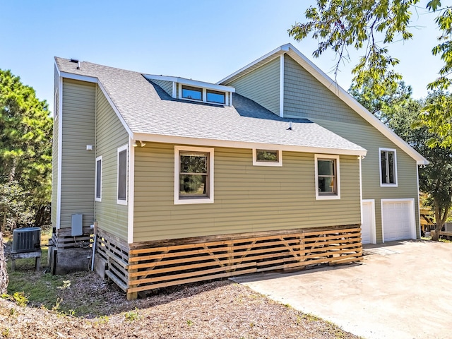 view of home's exterior with central AC unit and roof with shingles