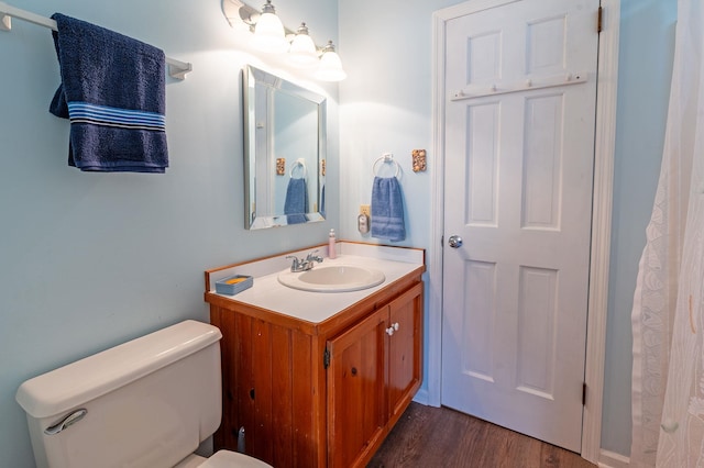 bathroom featuring toilet, wood finished floors, and vanity