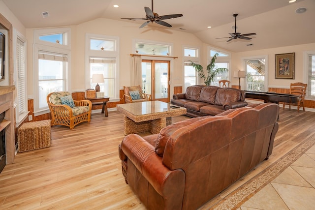 living area featuring lofted ceiling, light wood finished floors, a fireplace, and visible vents